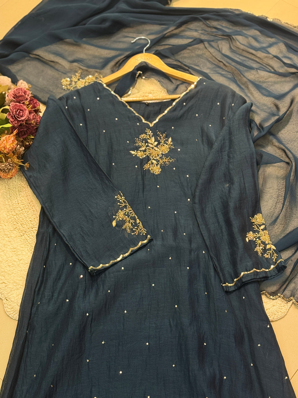 Navy blue dress with gold embroidery on a beige surface